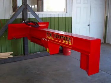 A red hydraulic log splitter sitting in a room with a window and a door. The splitter has a vertical beam attached to a horizontal beam, with a wedge on the end of the vertical beam. There is a control panel on the side of the machine.